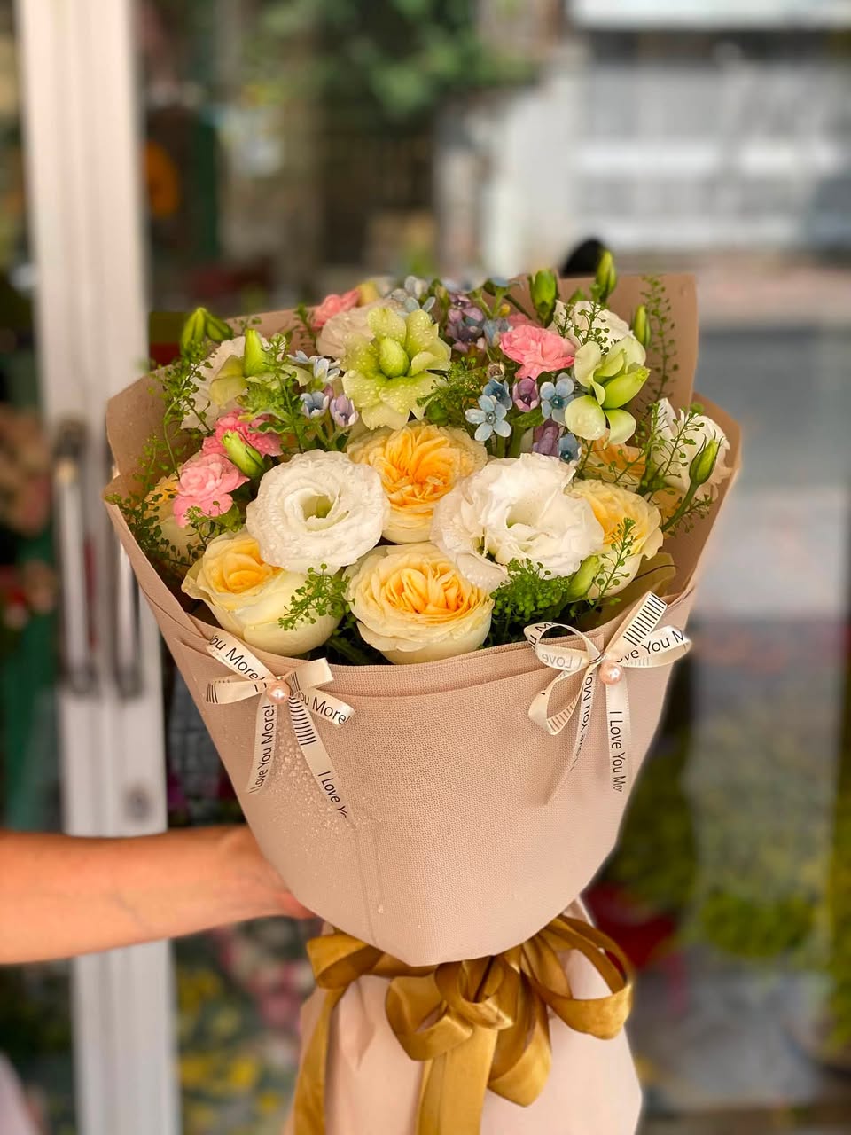 Bó hoa hồng kem và cam gói giấy nâu, buộc nơ vàng